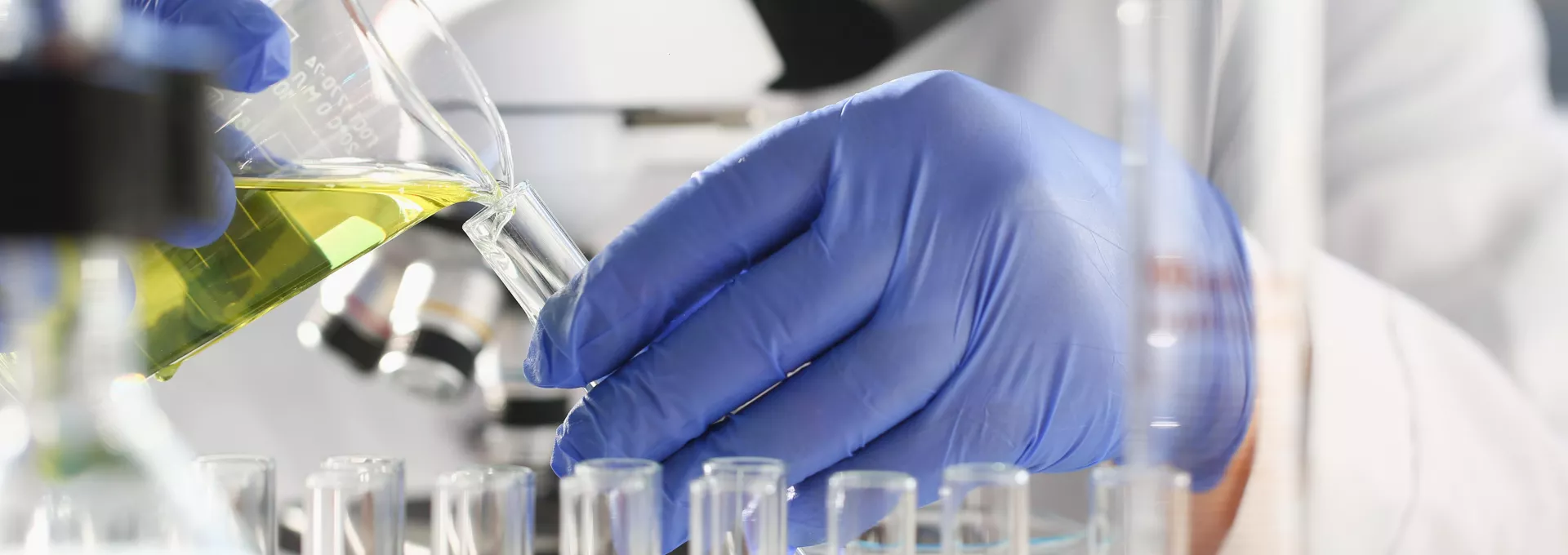 A male chemist holds test tube of glass in his hand in a lab