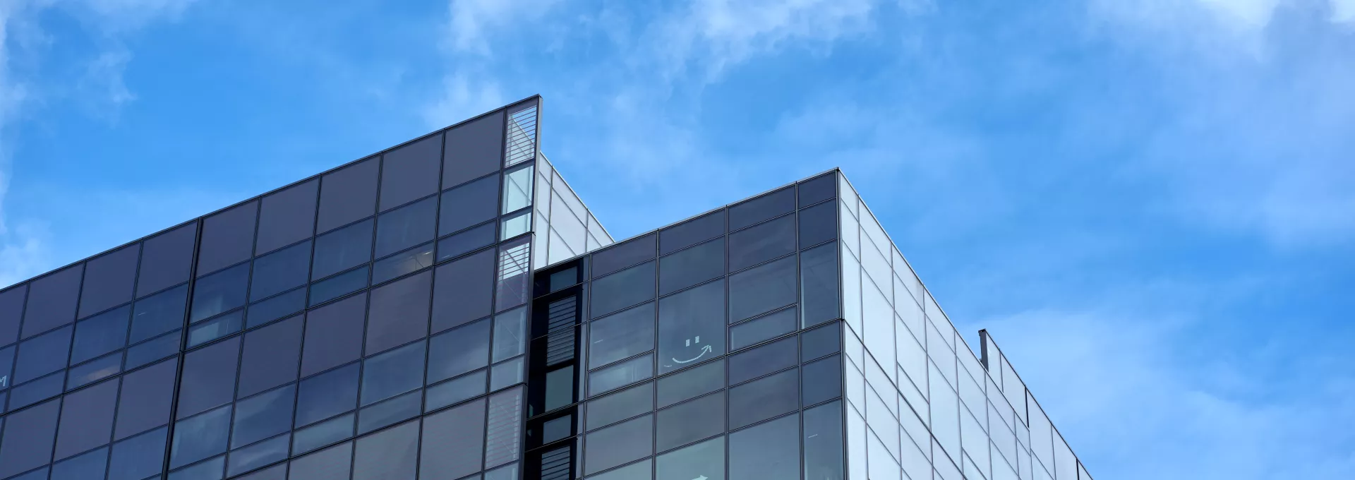 building with glass in a cloudy blue sky