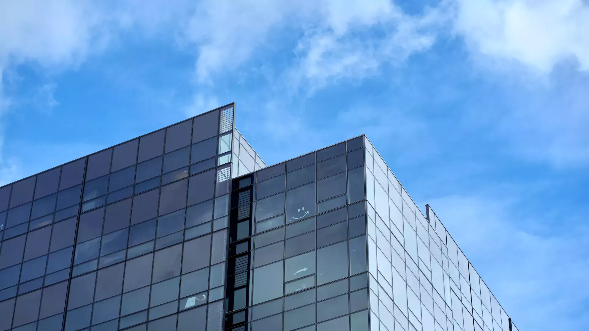 building with glass in a cloudy blue sky