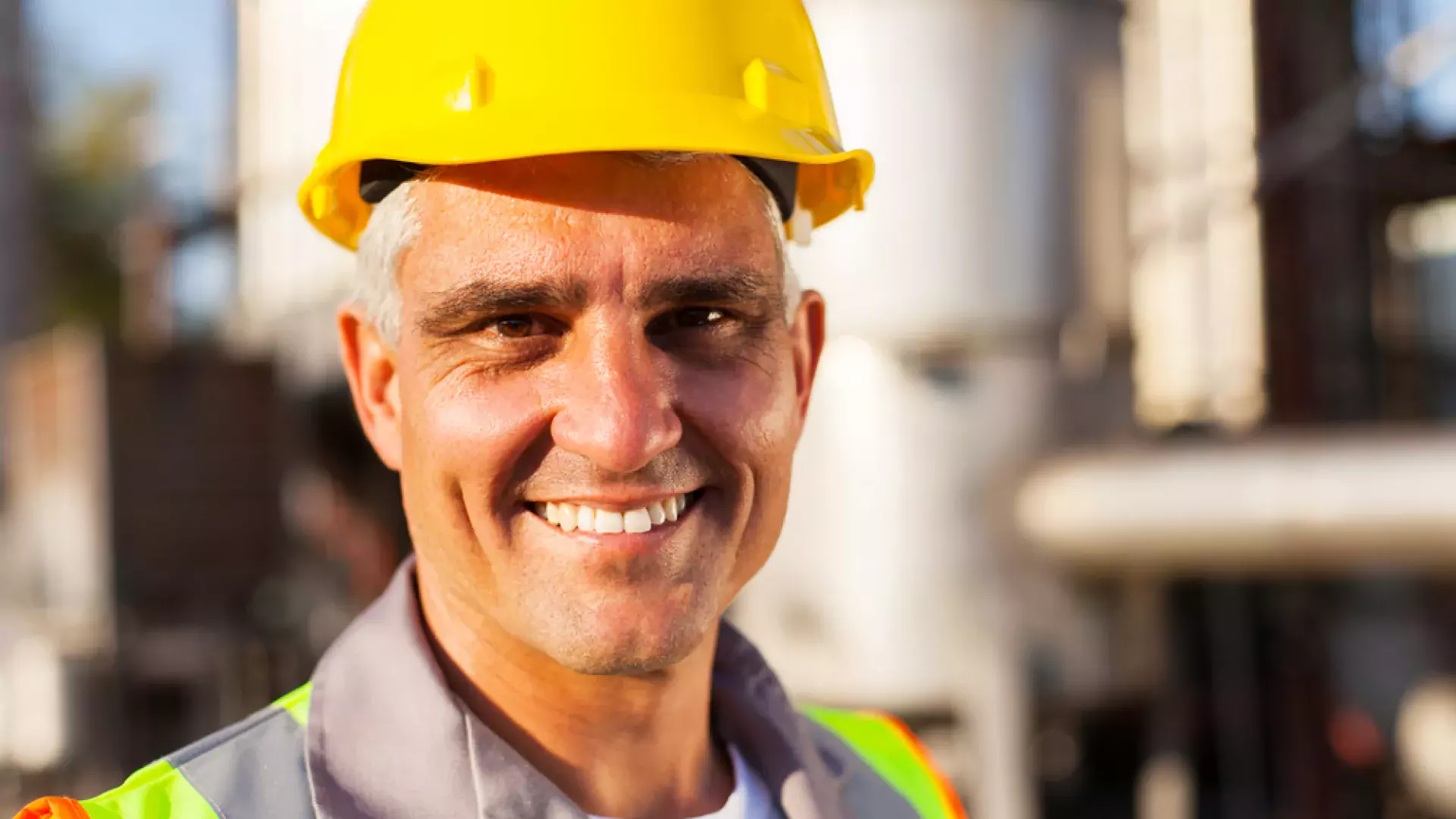 man smiling wearing an helmet and a safety jacket 