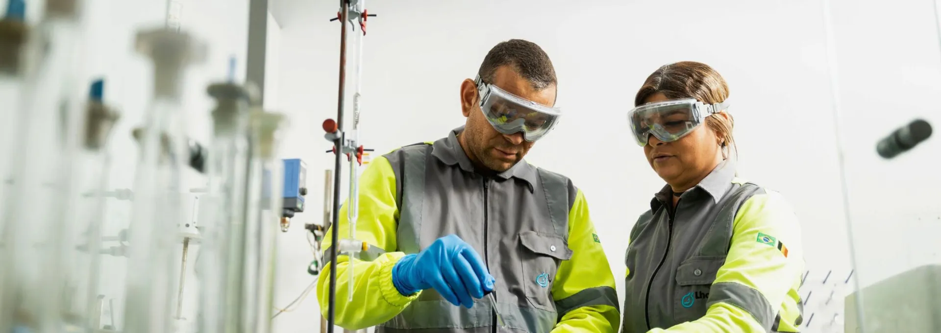 Two Lhoist employees conducting laboratory testing and handling samples while wearing protective equipment in Brazil.