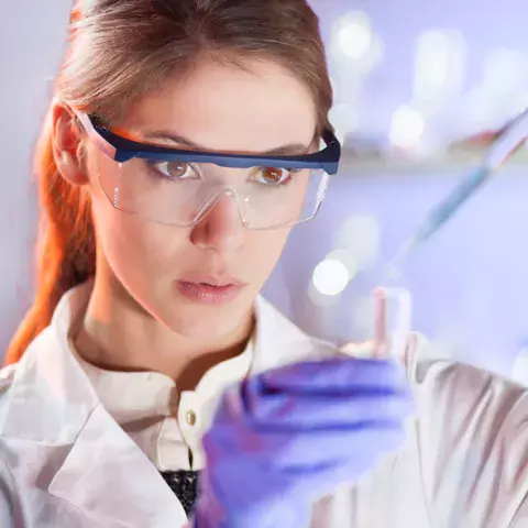 woman with protective glasses working in chemistry lab