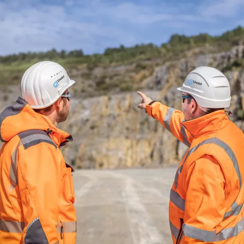 two men in a quarry watching and pointing at something in the background