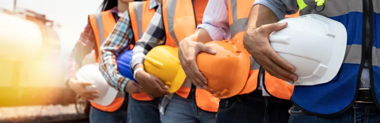 Teamwork of diversity engineer holding helmet standing in row on site work 