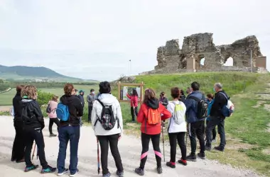 group of Nordic walkers stopping in front of an information board with a ruin in the background