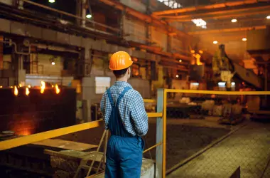 man looking at the machines in a steel factory from a distance