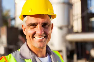 man smiling wearing an helmet and a safety jacket 