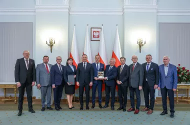 Group of people receiving an award in front of Polish flags