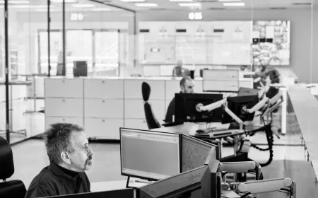 man sitting in front of computers and working on it