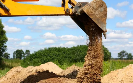 Yellow excavator shovel digging pit in ground