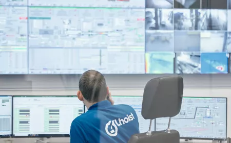 View on the back of a man with blue shirt in front of screens