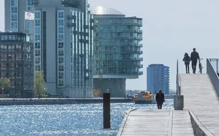 2 people on a bridge, walking towards an office building