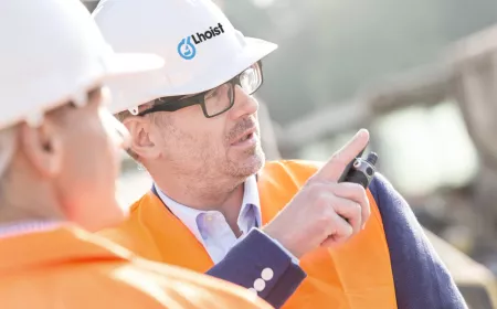 Discussion between two persons on-site. One is pointing at something. They are wearing safety equipment
