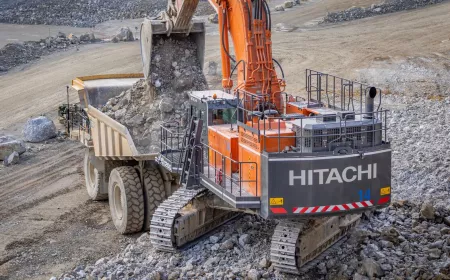 Large excavator loading rock into a dump truck in an open quarry site