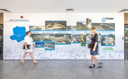 Interior wall display illustrating Lhoist’s operations in Central Europe, featuring a regional map, site photographs, and a timeline of key milestones, with employees walking through the workspace.