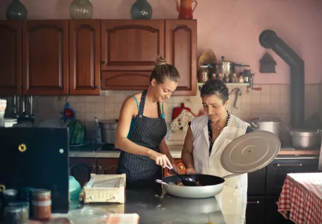 young and elderly women preparing a meal in a kitchen